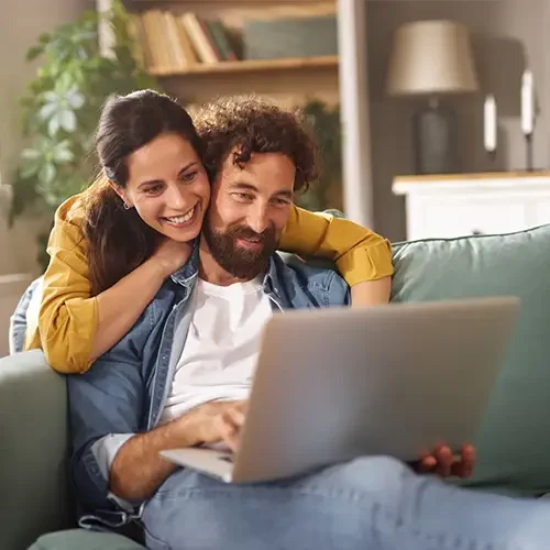 A woman and a man on the couch with a laptop.