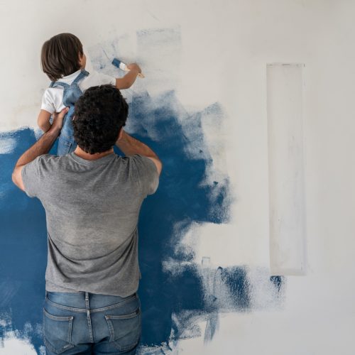 Boy helping his father painting the house