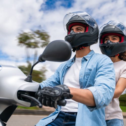 Happy young Latin American couple riding their motorcycle outdoors - road trip concepts