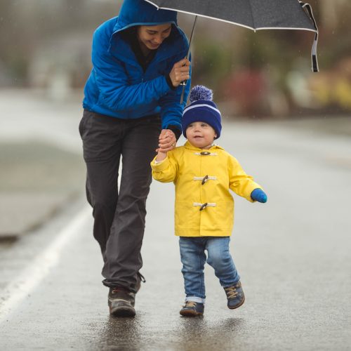 Young mom doesn't let the rain stop her from taking her young boy on a joyful walk